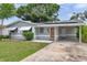Gray single-story home featuring solar panels, a covered front entrance, and an attached carport at 6497 43Rd N Ave, Kenneth City, FL 33709