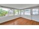 Bright sunroom with hardwood floors, surrounded by windows offering backyard views, and a door leading outside at 6497 43Rd N Ave, Kenneth City, FL 33709