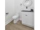 Small powder room features a modern circular mirror, gray countertop, and white toilet and cabinets at 723 W 113Th Ave, Tampa, FL 33612