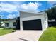 Modern single-Gathering home featuring a sleek black garage door, well-maintained lawn, and blue skies at 723 W 113Th Ave, Tampa, FL 33612