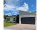 Modern home exterior featuring clean lines, a black garage door, and well-manicured lawn at 723 W 113Th Ave, Tampa, FL 33612