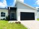 Charming home with a modern design, featuring a black garage door, stylish front door, and a green lawn at 723 W 113Th Ave, Tampa, FL 33612