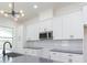 Bright kitchen features white cabinets, light gray countertops, stainless steel microwave, and a modern light fixture at 723 W 113Th Ave, Tampa, FL 33612