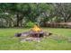 Spacious backyard featuring a fire pit, mature trees, and lush green grass at 8248 Irene St, Zephyrhills, FL 33540