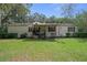 Quaint single-story home featuring mature trees, a covered porch, and an American flag at 8248 Irene St, Zephyrhills, FL 33540