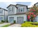 Charming two-story townhome featuring gray siding, a two-car garage, and colorful landscaping at 9140 Hillcroft Dr, Riverview, FL 33578