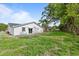 Large backyard showcasing a well-kept lawn, mature trees, and a sliding glass door leading to outdoor living space at 9511 N Hyaleah Rd, Tampa, FL 33617