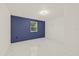 An empty bedroom with a blue accent wall, marble floors, and a window at 9511 N Hyaleah Rd, Tampa, FL 33617