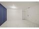 A spacious, bright room featuring modern blue accent wall and pristine white tile flooring at 9511 N Hyaleah Rd, Tampa, FL 33617
