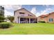 Back of home with green lawn, screened in patio and balcony with outdoor seating at 9800 Sago Point Dr, Seminole, FL 33777