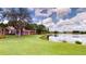 Scenic backyard view of the house, pond and green lawn on a sunny day at 9800 Sago Point Dr, Seminole, FL 33777