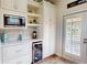 Modern bar area with wine fridge, microwave and wine glass rack near door with plantation shutters at 9800 Sago Point Dr, Seminole, FL 33777