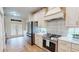 Modern kitchen with stainless steel fridge, gas range, shaker cabinets, and view to sunroom through shuttered doors at 9800 Sago Point Dr, Seminole, FL 33777