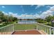 Balcony view overlooking a serene lake, showcasing lush landscaping and picturesque blue skies with fluffy white clouds at 9800 Sago Point Dr, Seminole, FL 33777