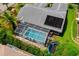 Aerial view of a screened-in pool, solar panels, trampoline, and lush landscaping in the backyard at 10228 Yellow Pine Way, Hudson, FL 34667