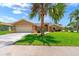 Charming single-story home featuring a two-car garage, manicured lawn, and mature palm trees at 10228 Yellow Pine Way, Hudson, FL 34667