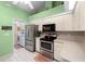 Well-equipped kitchen with stainless steel appliances and white cabinetry next to laundry room at 10228 Yellow Pine Way, Hudson, FL 34667