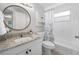 Bright bathroom with granite countertop, round mirror, and shower-tub combination with floral shower curtain at 10599 111Th N Ave, Largo, FL 33773