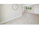 Neutral living room with large clock, tile flooring, large windows and easy access to entry door at 10599 111Th N Ave, Largo, FL 33773