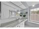 Bathroom with a large mirror, white vanity, gray marble countertop, and natural light from the window at 10611 131St St, Largo, FL 33774