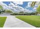 Long white driveway with carport access leading to a charming home with well-manicured lawn and landscaping at 10611 131St St, Largo, FL 33774