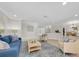 Inviting living room with a blue sofa, neutral armchairs, wood floors, and staircase at 10611 131St St, Largo, FL 33774