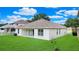 An exterior view of the home showing a well-manicured lawn with sliding glass doors leading to an outdoor patio at 10621 Ribbon Fern Way Way, Land O Lakes, FL 34638