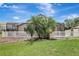 This backyard features a white fence, and large palm trees behind a lush green lawn at 10734 Banfield Dr, Riverview, FL 33579