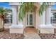 Home's front entrance, showing the double glass doors with brick pavers, white columns and tropical landscaping at 10734 Banfield Dr, Riverview, FL 33579