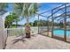 Paver patio with screened enclosure, offering scenic backyard views and tropical landscaping at 10734 Banfield Dr, Riverview, FL 33579
