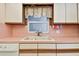 Kitchen sink with white cabinetry, pink countertops, and window at 11000 Gulf Blvd # 703, Treasure Island, FL 33706