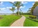 Lush backyard landscaping with manicured lawn, a stone pathway, and lake view at 11603 Heron Watch Pl, Riverview, FL 33569