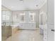Bright bathroom featuring dual vanities, a soaking tub with a glass shower, and neutral tile flooring at 11603 Heron Watch Pl, Riverview, FL 33569