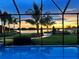 Enclosed backyard pool boasts picturesque lake views and vivid colors from the evening sunset at 11603 Heron Watch Pl, Riverview, FL 33569