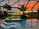 Backyard pool featuring a spa, chaise lounges and scenic views of the lake and bright sunset at 11603 Heron Watch Pl, Riverview, FL 33569