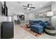 Open concept living room with tile flooring, ceiling fan, blue sectional, and kitchen view at 12729 Flatwood Creek Dr, Gibsonton, FL 33534