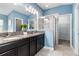 Well-lit main bathroom featuring double vanity, large mirror, walk-in shower, and a walk-in closet at 12729 Flatwood Creek Dr, Gibsonton, FL 33534