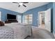 Inviting main bedroom showcasing blue walls, plush bed, tv, vaulted ceiling, and a bright en-suite bathroom at 12729 Flatwood Creek Dr, Gibsonton, FL 33534