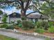 A charming home with a lush landscaped yard is shaded by a large, mature tree at 16134 Ravendale Dr, Tampa, FL 33618