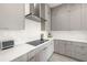 Modern kitchen features stainless steel range hood, sleek countertops, and grey cabinets, with stylish backsplash at 1625 55Th S St, Gulfport, FL 33707