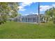 Lush backyard featuring manicured lawn, mature trees and a screened-in pool area at 16317 Colwood Dr, Odessa, FL 33556