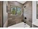 Stylish bathroom featuring tub, tiled walls, and a window with natural light at 16317 Colwood Dr, Odessa, FL 33556