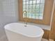 Close-up of a modern standalone tub with gold faucet fixtures, set against a distinctive glass block window at 16317 Colwood Dr, Odessa, FL 33556