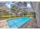 Inviting swimming pool in screened-in lanai with surrounding paver patio and lush landscaping at 16317 Colwood Dr, Odessa, FL 33556
