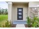 Modern front door with glass panels, framed by stone accents and manicured landscaping at 1680 Hazy Sea Dr, Plant City, FL 33565