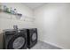 Convenient laundry room equipped with sleek, black Samsung washer and dryer, and shelving at 1680 Hazy Sea Dr, Plant City, FL 33565