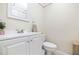 Compact powder room with a white vanity, toilet, and decorative mirror and accents at 19029 Us Highway 19 N # 3-1, Clearwater, FL 33764