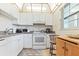 Bright kitchen featuring white cabinetry, appliances, tile backsplash, and natural light from a window at 19029 Us Highway 19 N # 3-1, Clearwater, FL 33764