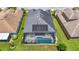 Aerial view of the property showcasing the pool, patio, and solar panels on the roof at 1958 Marshberry Ct, Trinity, FL 34655
