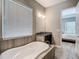 Bright bathroom features a soaking tub, granite vanity, and an open doorway to the bedroom at 1958 Marshberry Ct, Trinity, FL 34655